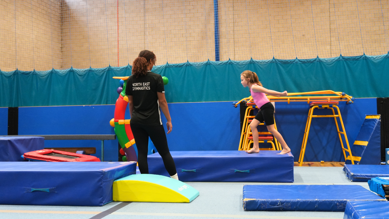 gymnast running observed by north east gymnastics academy coach