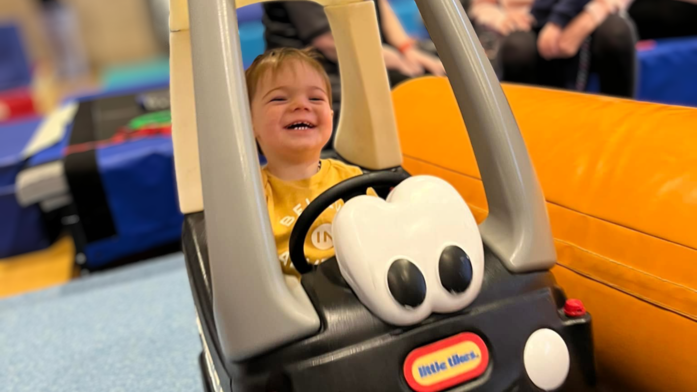small boy playing in a toy car at stay and play class