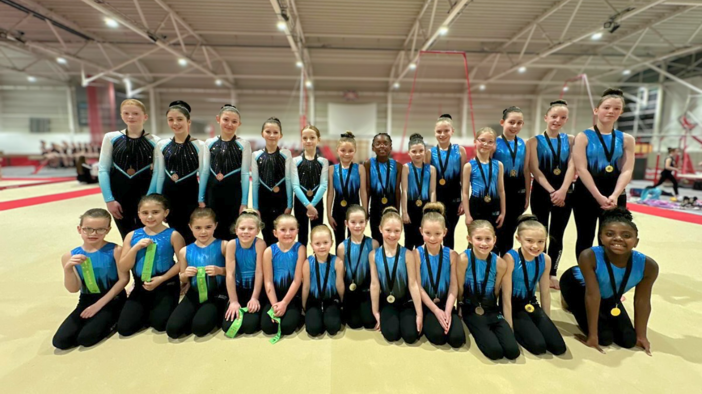 teamgym squad gymnasts with medals and ribbons at a competition