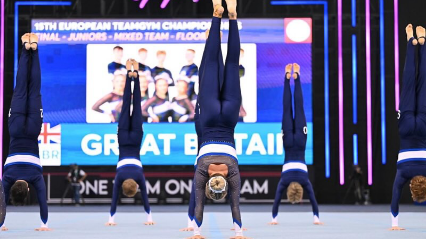teamgym gymnasts on floor doing a handstand